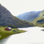Blick über den Fjord mit rotem norwegischem Holzhaus